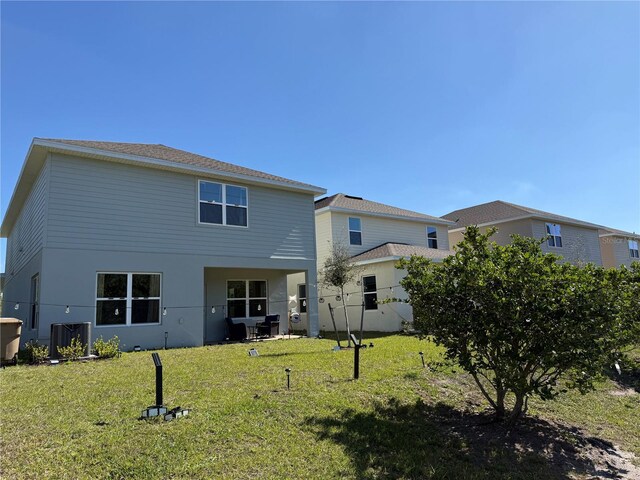 rear view of property featuring cooling unit, a lawn, and stucco siding