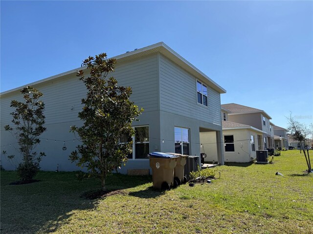 back of property featuring a lawn and central AC