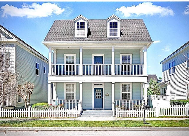 view of front of property featuring a fenced front yard, covered porch, a shingled roof, and a balcony