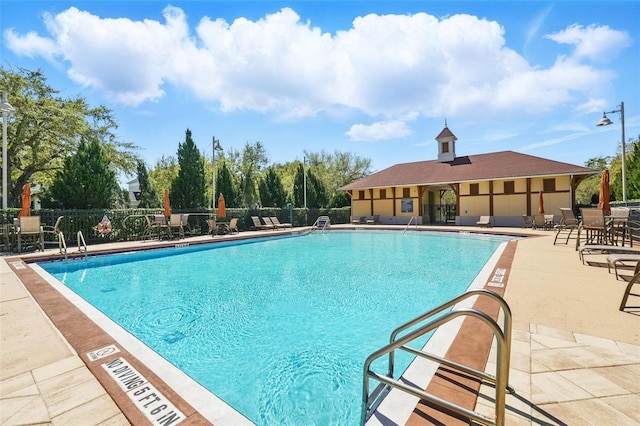 community pool with a patio area and fence