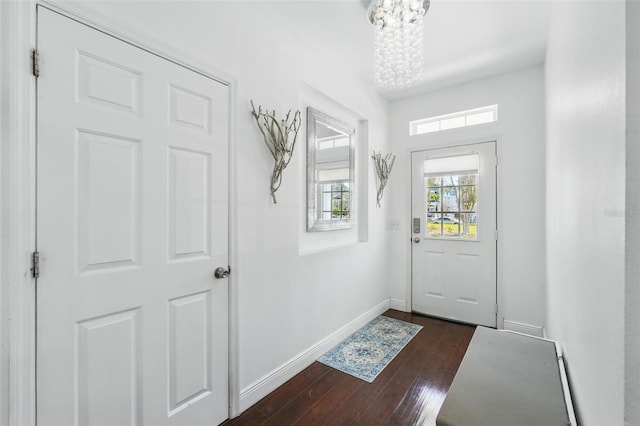 entryway with a chandelier, dark wood-type flooring, and baseboards