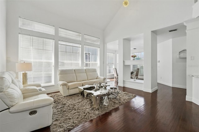 living room with visible vents, wood finished floors, baseboards, and high vaulted ceiling