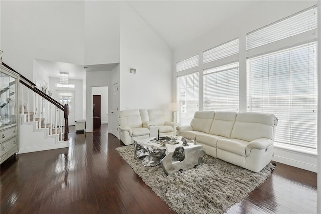 living room featuring dark wood-style floors, high vaulted ceiling, stairs, and baseboards