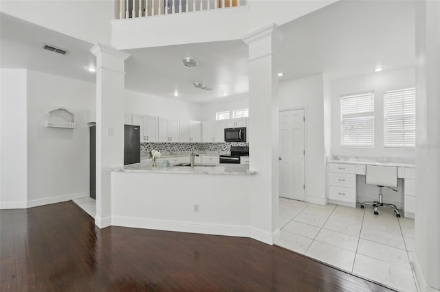 kitchen featuring visible vents, ornate columns, a sink, decorative backsplash, and black appliances