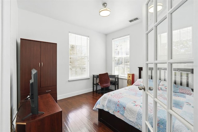 bedroom with visible vents, baseboards, and dark wood-type flooring