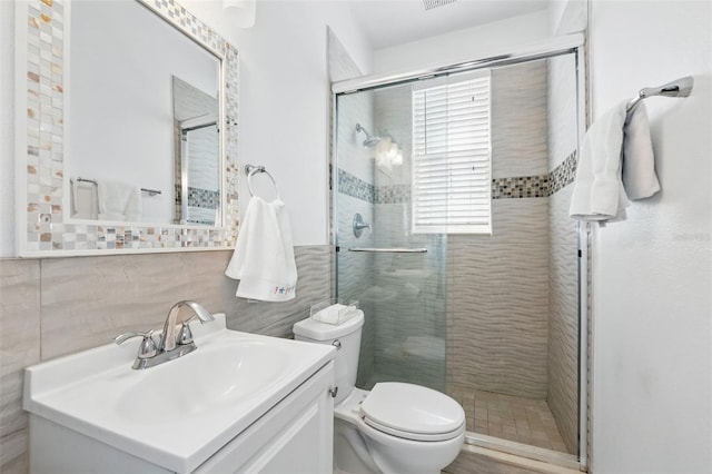 bathroom featuring vanity, a shower stall, tile walls, toilet, and backsplash