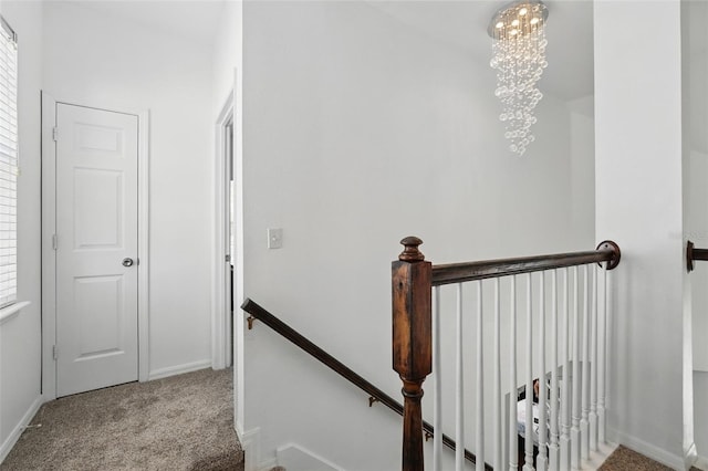 stairway featuring baseboards, an inviting chandelier, and carpet flooring