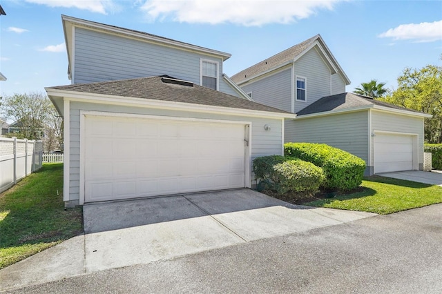 traditional-style home with an attached garage, fence, driveway, and roof with shingles