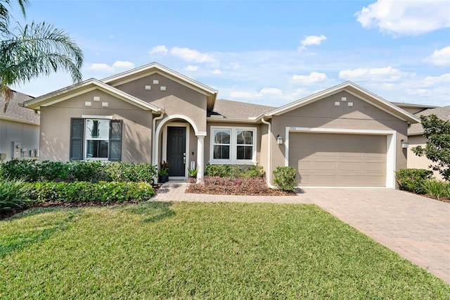 single story home featuring stucco siding, decorative driveway, a garage, and a front lawn