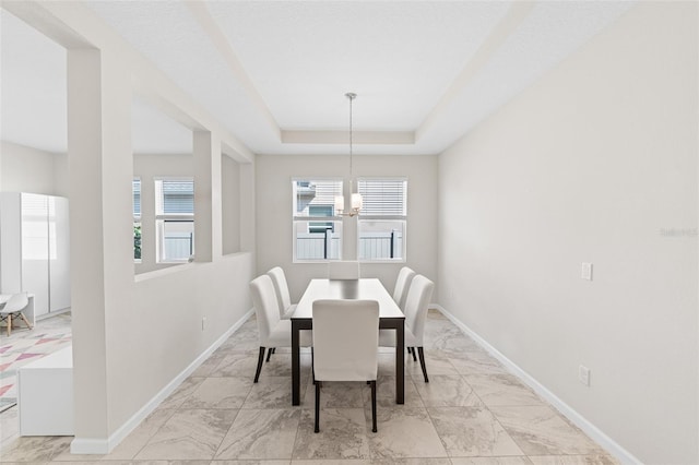 dining space with marble finish floor, baseboards, and a tray ceiling