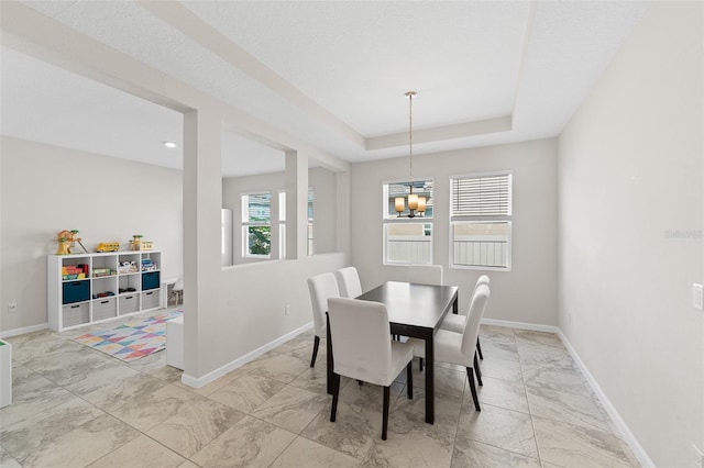 dining room with a raised ceiling, baseboards, and marble finish floor