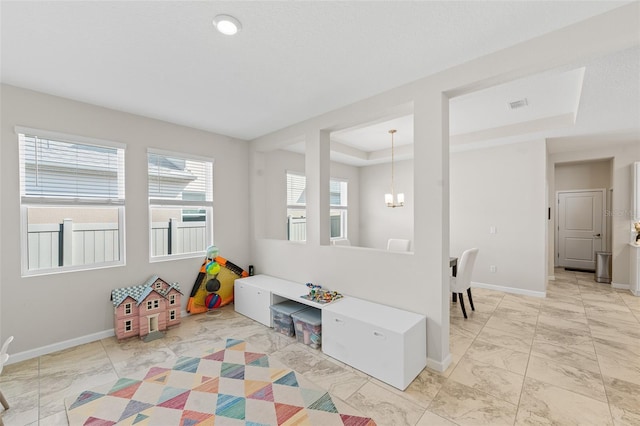 rec room with visible vents, marble finish floor, a tray ceiling, baseboards, and a chandelier