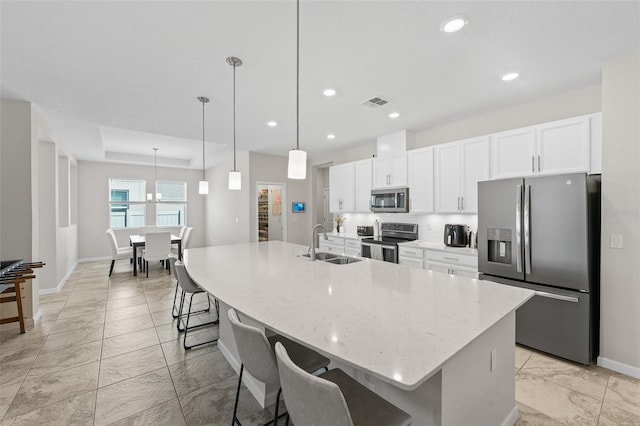 kitchen with a large island, a sink, white cabinetry, stainless steel appliances, and a breakfast bar area