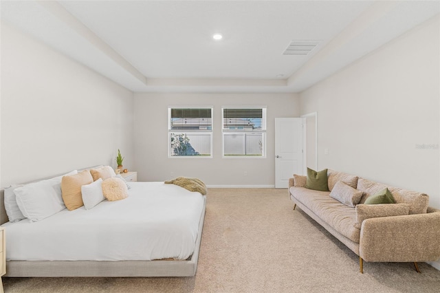 bedroom with light carpet, visible vents, a raised ceiling, and baseboards