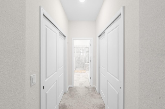 hallway featuring carpet flooring and a textured wall