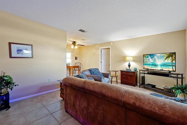 living area featuring baseboards, visible vents, light tile patterned flooring, ceiling fan, and a textured ceiling