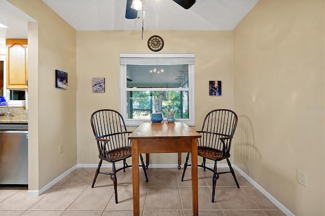 dining room with light tile patterned flooring, a textured ceiling, baseboards, and a ceiling fan