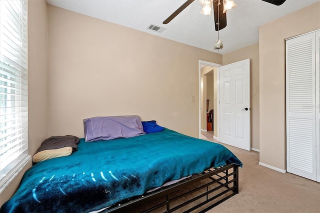 bedroom with visible vents, carpet floors, multiple windows, and ceiling fan