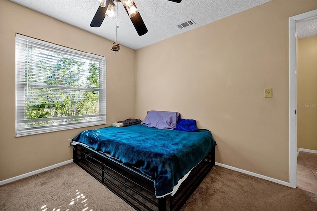 bedroom featuring a textured ceiling, carpet, visible vents, and baseboards