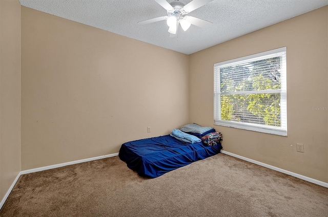 carpeted bedroom with ceiling fan, a textured ceiling, and baseboards