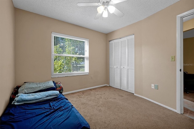 bedroom with a closet, carpet flooring, a textured ceiling, and baseboards