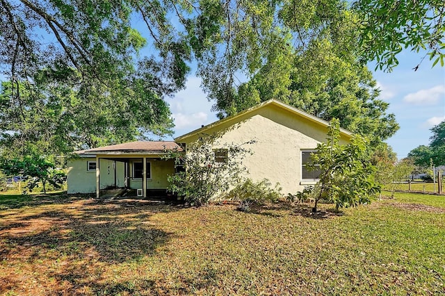 back of property with stucco siding and a yard