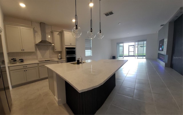 kitchen with tasteful backsplash, visible vents, black electric stovetop, light countertops, and wall chimney exhaust hood