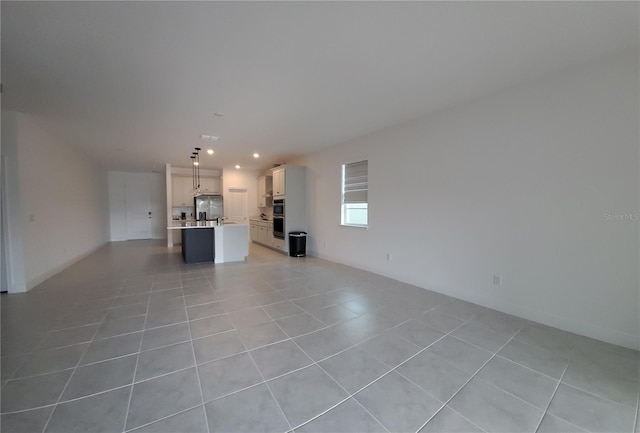 unfurnished living room featuring light tile patterned floors, recessed lighting, and a sink