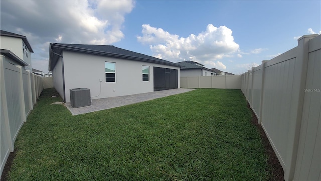 back of house featuring central AC unit, a yard, a fenced backyard, stucco siding, and a patio area