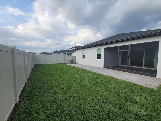 view of yard with a patio, a fenced backyard, and a sunroom