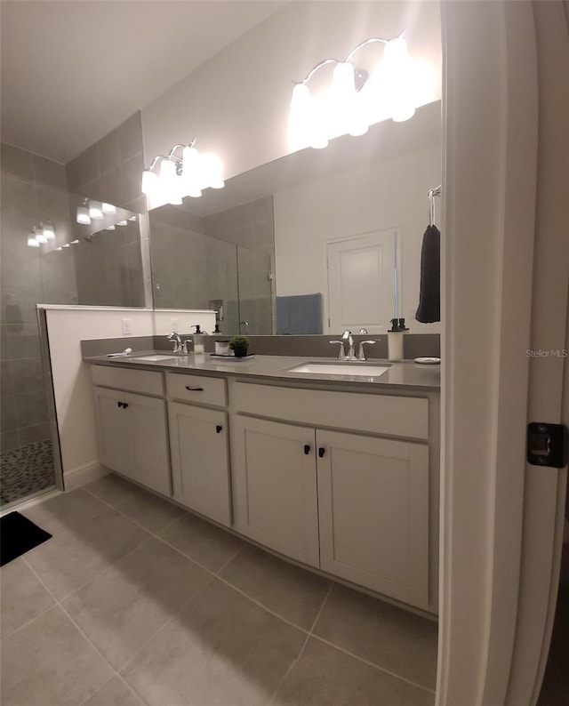 bathroom with tile patterned floors, tiled shower, double vanity, and a sink