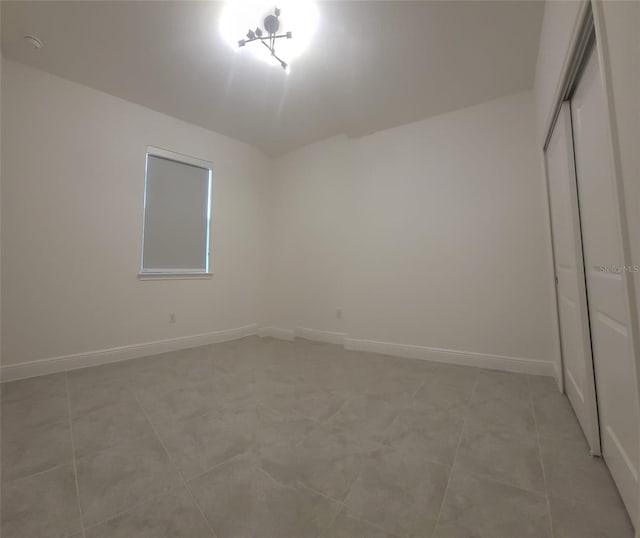 unfurnished bedroom featuring a closet, light tile patterned floors, and baseboards