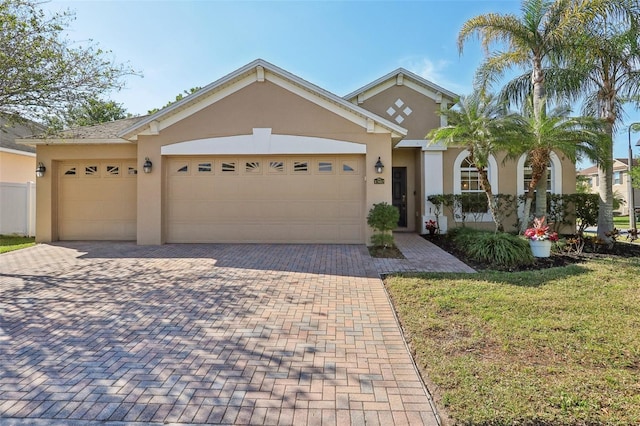 view of front of property with stucco siding, an attached garage, and decorative driveway