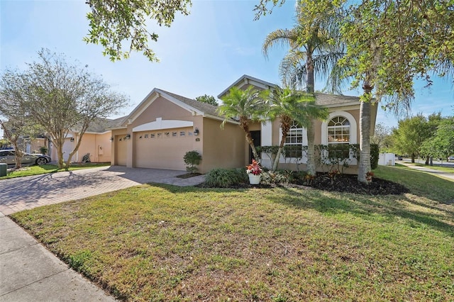 ranch-style house with a front yard, decorative driveway, an attached garage, and stucco siding