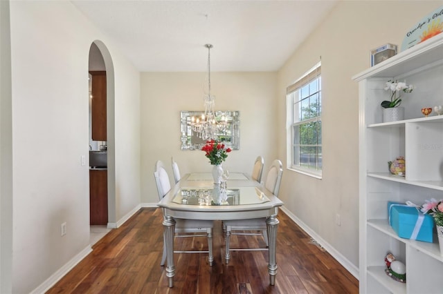 dining area with built in shelves, wood finished floors, arched walkways, and baseboards