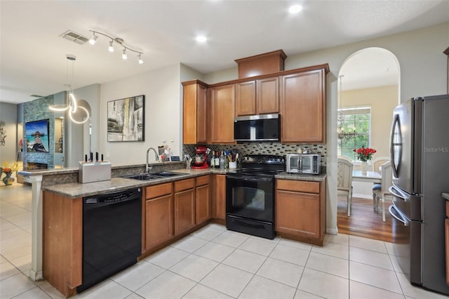 kitchen featuring black appliances, brown cabinetry, visible vents, and a sink