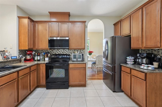 kitchen featuring decorative backsplash, brown cabinets, appliances with stainless steel finishes, and a sink