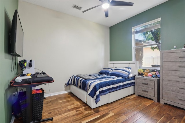 bedroom featuring a ceiling fan, wood finished floors, visible vents, and baseboards