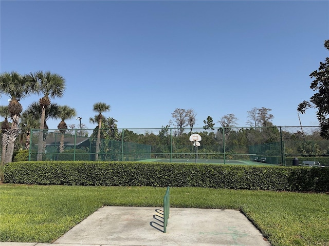 view of tennis court featuring community basketball court, a yard, and fence