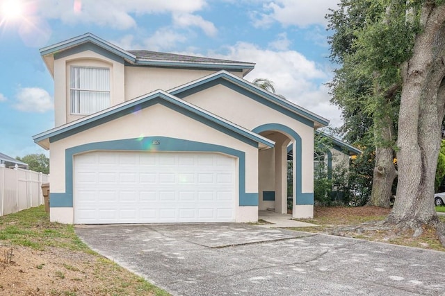 view of front of property featuring stucco siding, concrete driveway, a garage, and fence