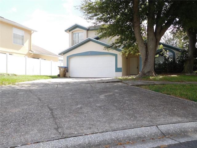 view of front of house with stucco siding, an attached garage, driveway, and fence