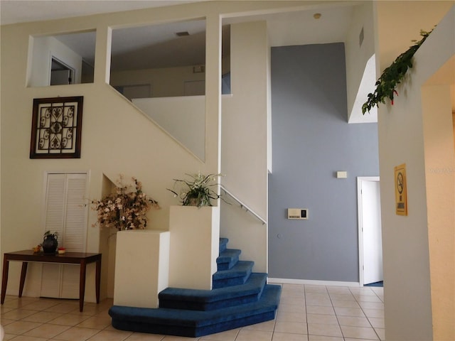 stairs featuring tile patterned flooring and a towering ceiling