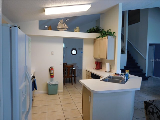 kitchen with a sink, white fridge with ice dispenser, a peninsula, and light tile patterned floors