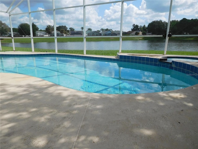 view of pool featuring a water view, a patio, a lanai, and a pool with connected hot tub