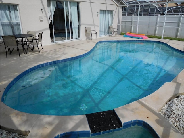 view of swimming pool with a patio area, a fenced in pool, and glass enclosure