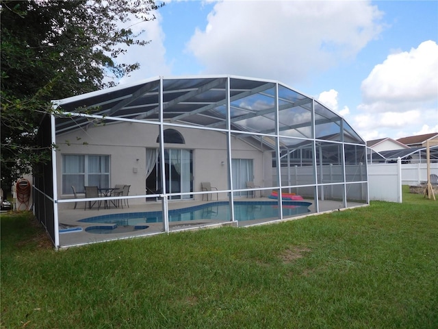 back of property featuring stucco siding, a lawn, a patio, glass enclosure, and a fenced in pool