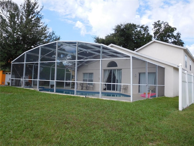 rear view of house featuring an outdoor pool, stucco siding, a lawn, and a lanai