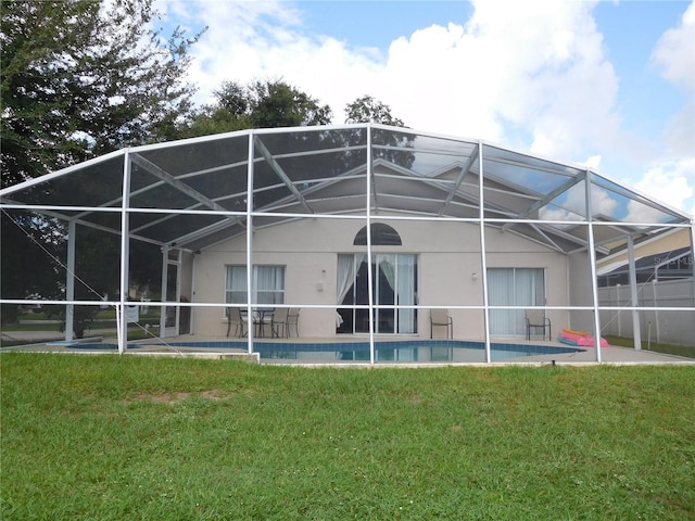 rear view of property with stucco siding, a patio, and a lawn