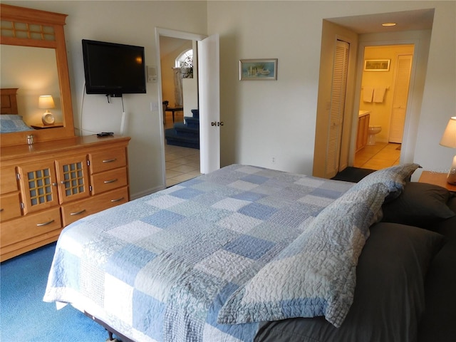 tiled bedroom with a closet, carpet, and ensuite bath