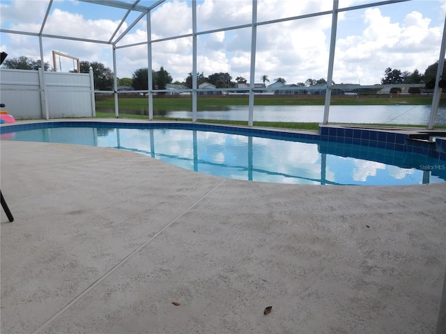 outdoor pool with glass enclosure, a water view, and a patio area